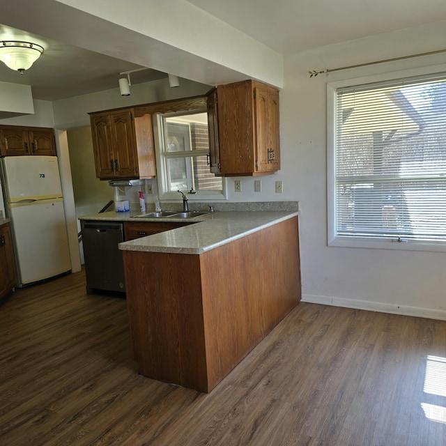 kitchen with dark wood finished floors, freestanding refrigerator, a sink, dishwasher, and a peninsula