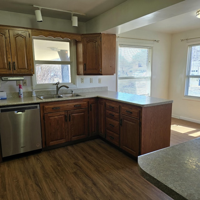 kitchen featuring dark wood finished floors, a peninsula, light countertops, stainless steel dishwasher, and a sink