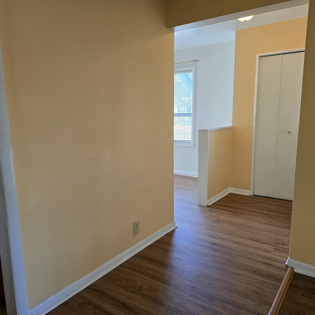 hall with dark wood-type flooring and baseboards