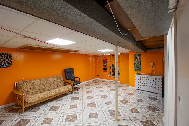 interior space featuring a paneled ceiling, tile patterned flooring, and baseboards