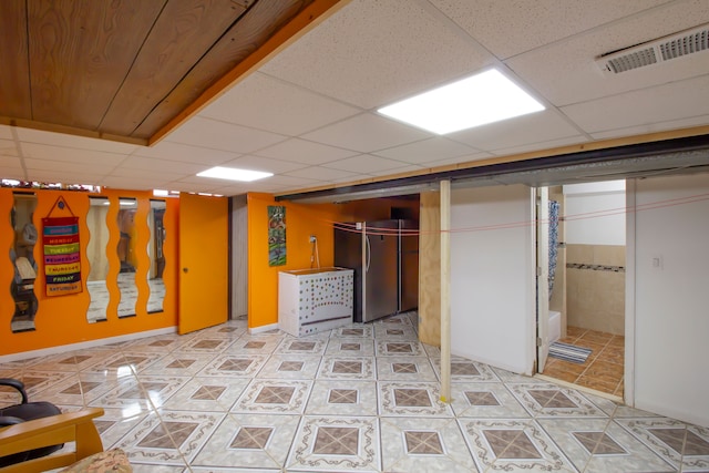 finished basement with visible vents, light tile patterned flooring, and a paneled ceiling