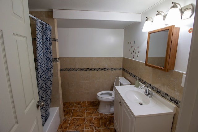 bathroom featuring toilet, tile walls, wainscoting, and vanity