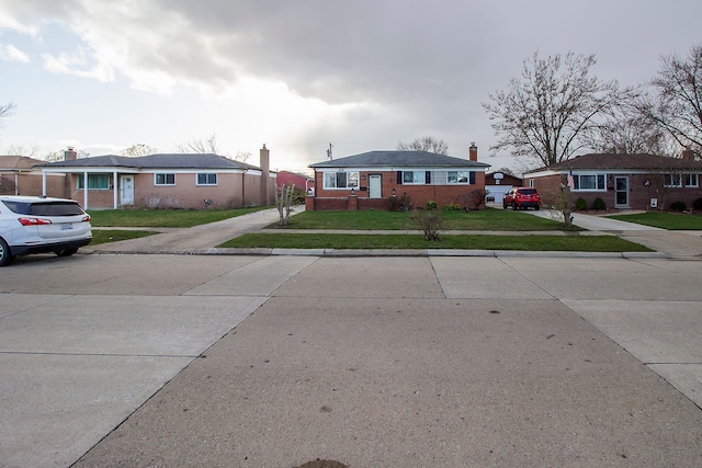 view of front facade featuring a front yard, concrete driveway, and brick siding