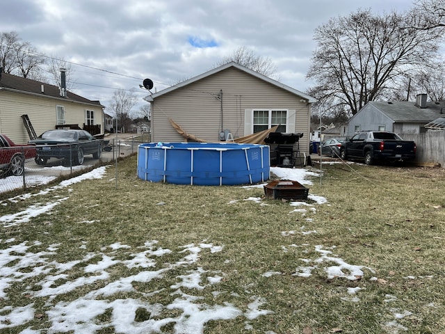 snow covered property with a yard, fence, and an outdoor pool