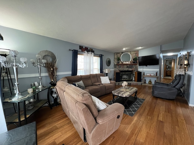 living area with wood finished floors and a stone fireplace