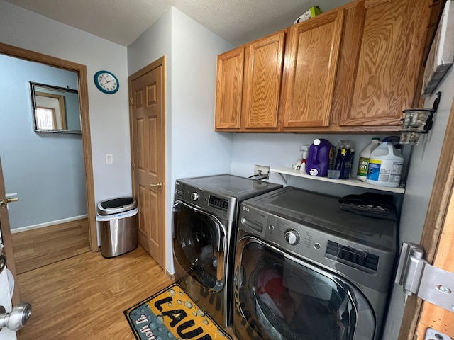 laundry area featuring washing machine and dryer, cabinet space, light wood-style flooring, and baseboards