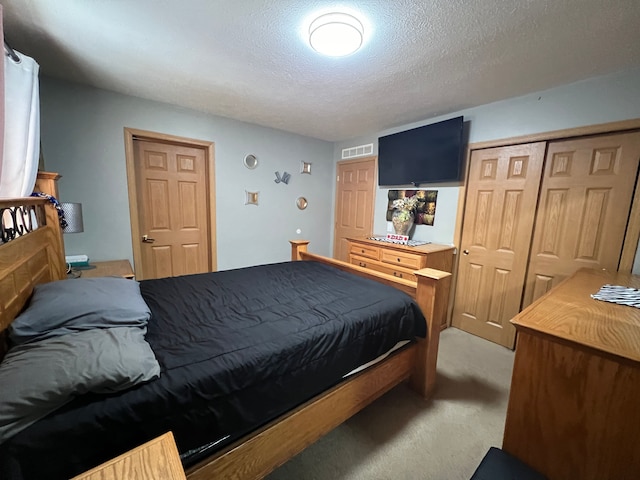 bedroom with light carpet, a textured ceiling, visible vents, and a closet