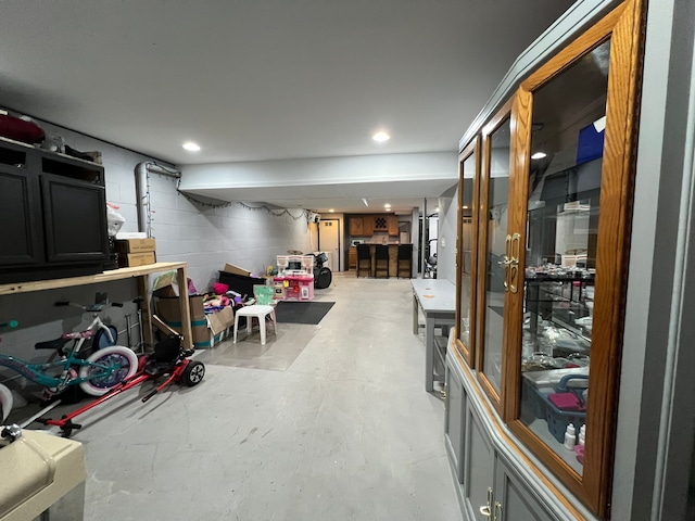 playroom with concrete block wall, concrete flooring, and recessed lighting