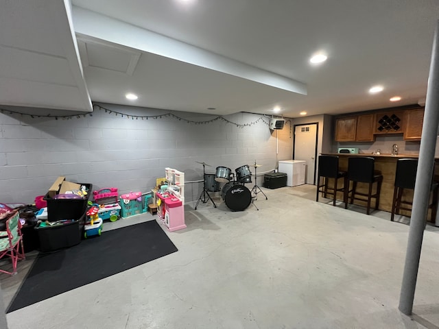 finished basement with a sink, bar area, concrete block wall, and recessed lighting