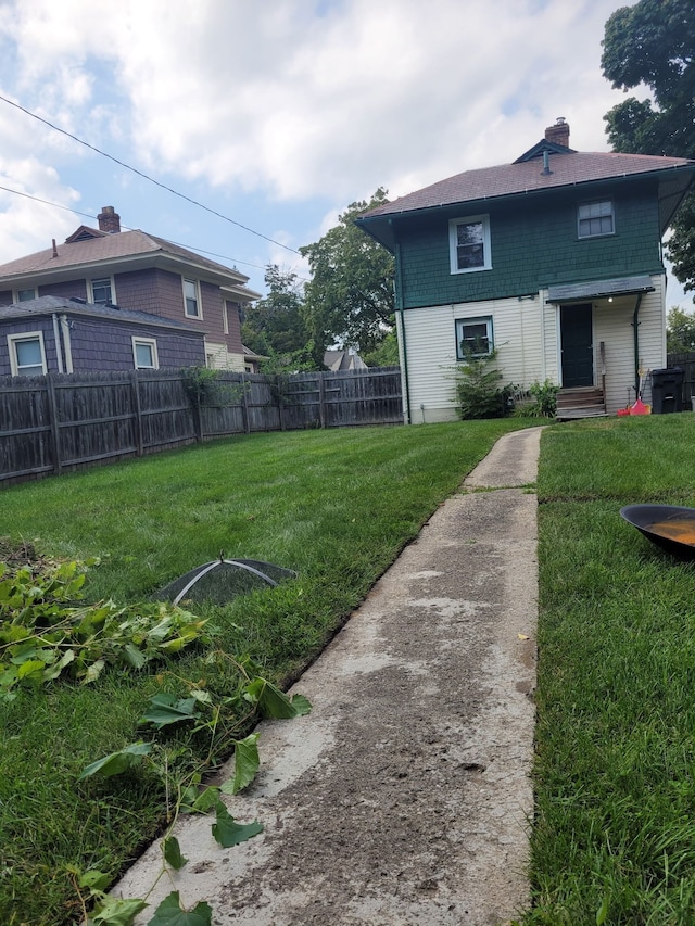 exterior space with entry steps, a lawn, a chimney, and fence