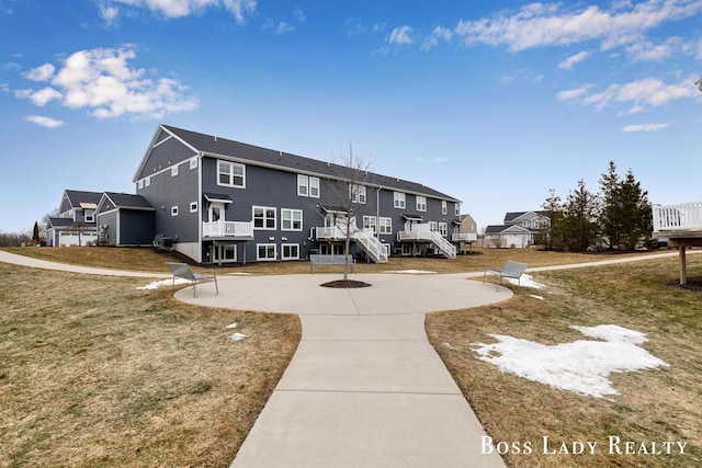 view of property's community with a deck, a patio, stairs, a yard, and a residential view