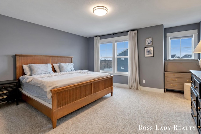 bedroom with multiple windows, light colored carpet, and baseboards