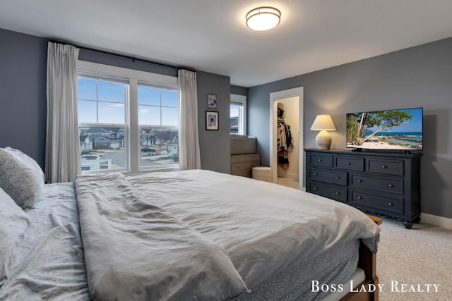 bedroom featuring light carpet, a spacious closet, baseboards, and a closet