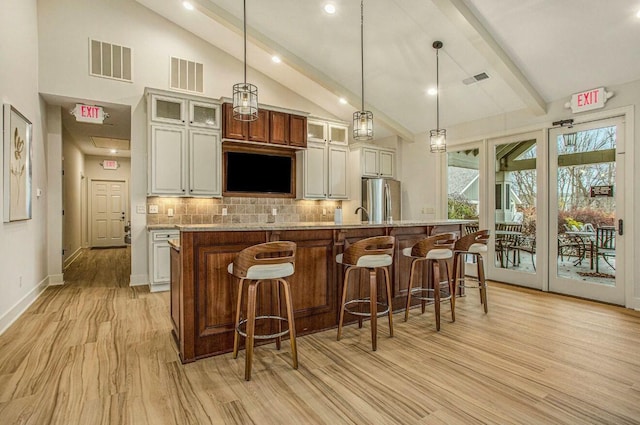 kitchen with light wood-style floors, freestanding refrigerator, visible vents, and backsplash