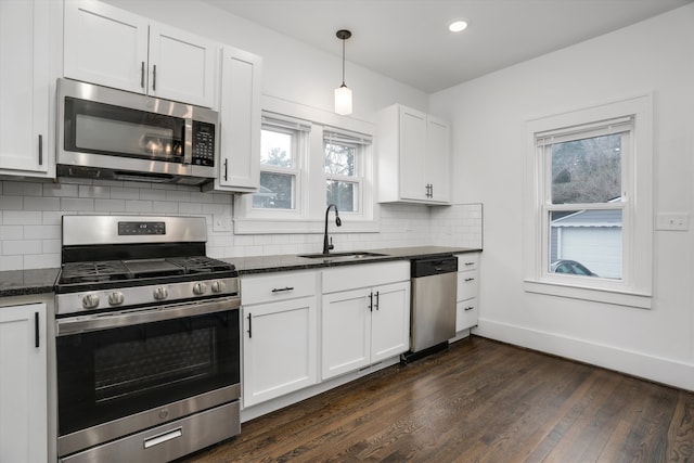 kitchen featuring stainless steel appliances, a sink, baseboards, tasteful backsplash, and dark wood finished floors