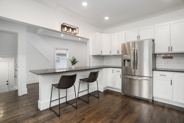 kitchen with a peninsula, dark wood-style flooring, white cabinets, and stainless steel fridge with ice dispenser