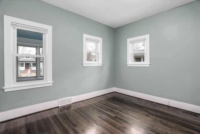 unfurnished room with dark wood-style floors, baseboards, and visible vents