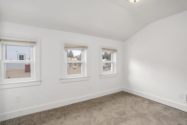 spare room with vaulted ceiling, carpet floors, and baseboards