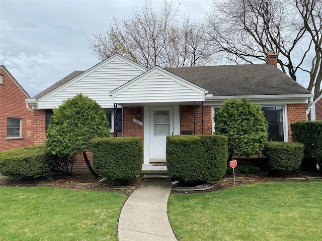 bungalow-style house with a front yard, brick siding, a chimney, and roof with shingles