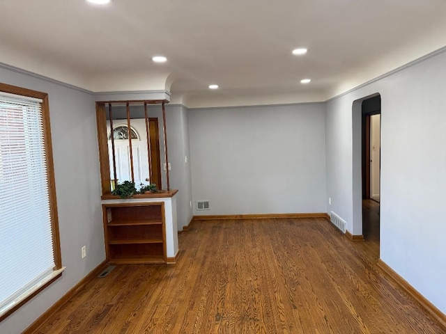 spare room with arched walkways, wood finished floors, visible vents, and recessed lighting