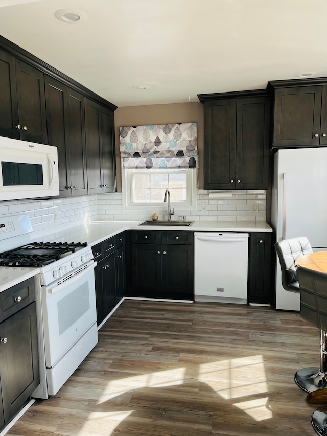 kitchen with white appliances, tasteful backsplash, light wood finished floors, and a sink