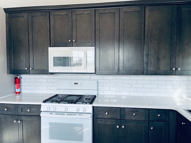 kitchen with light countertops, white appliances, backsplash, and dark brown cabinets