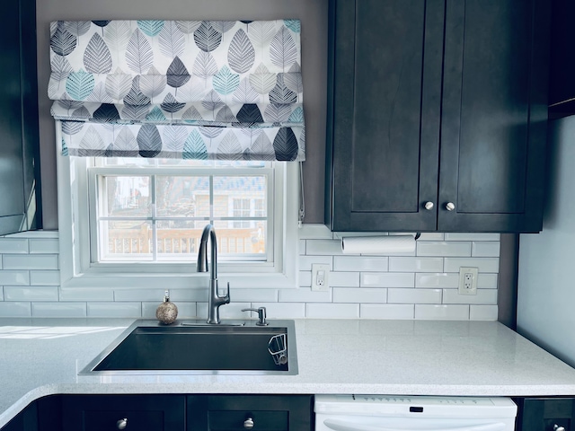 kitchen with dishwasher, light countertops, tasteful backsplash, and a sink