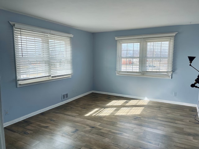 spare room featuring baseboards, visible vents, and wood finished floors