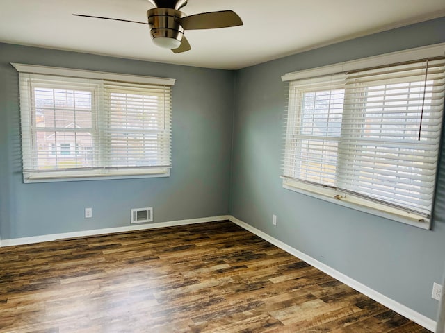 spare room with a ceiling fan, visible vents, baseboards, and wood finished floors