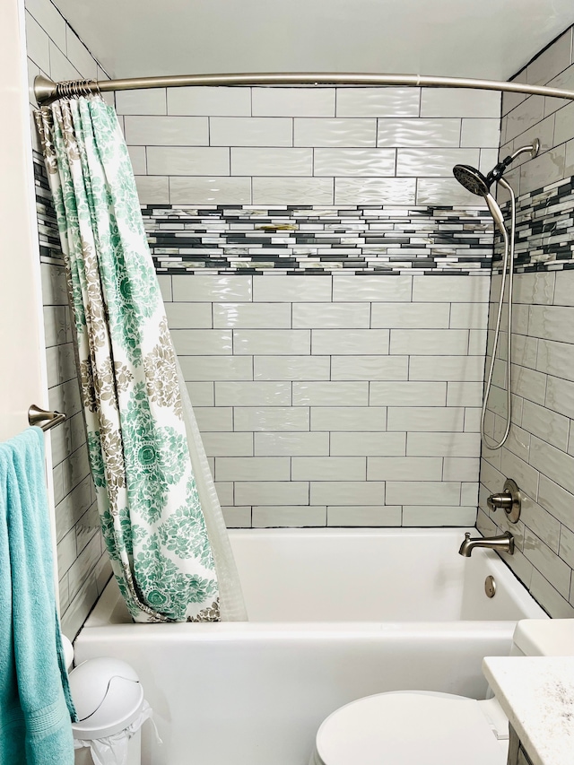 bathroom with shower / bathtub combination with curtain, toilet, and vanity