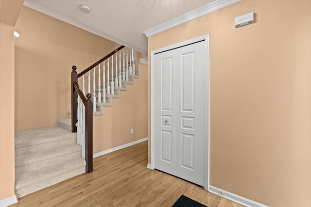 entryway featuring stairs, ornamental molding, light wood-type flooring, and baseboards