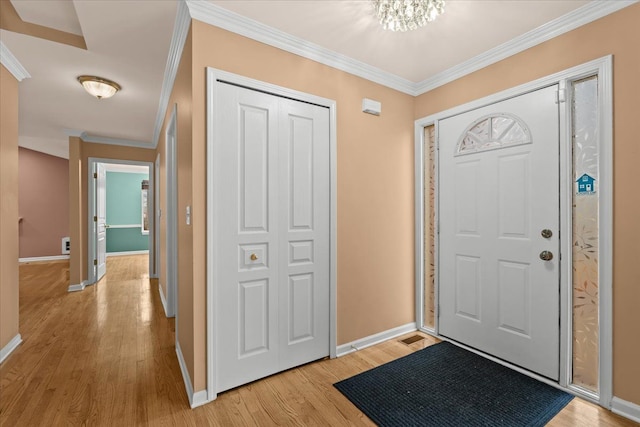 foyer entrance featuring baseboards, light wood-style flooring, and crown molding