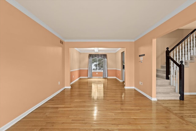 spare room featuring light wood-type flooring, crown molding, stairway, and baseboards