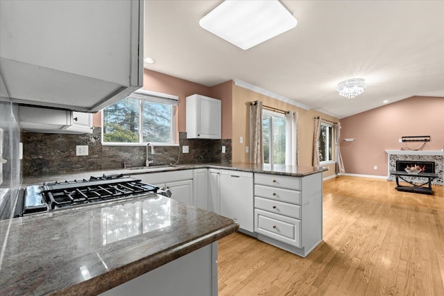 kitchen featuring lofted ceiling, open floor plan, a peninsula, white dishwasher, and gas stovetop