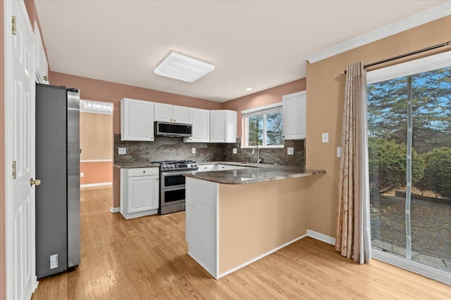 kitchen featuring a peninsula, white cabinetry, appliances with stainless steel finishes, and backsplash