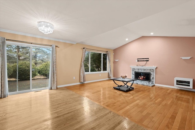 unfurnished living room with wood-type flooring, visible vents, vaulted ceiling, a lit fireplace, and baseboards