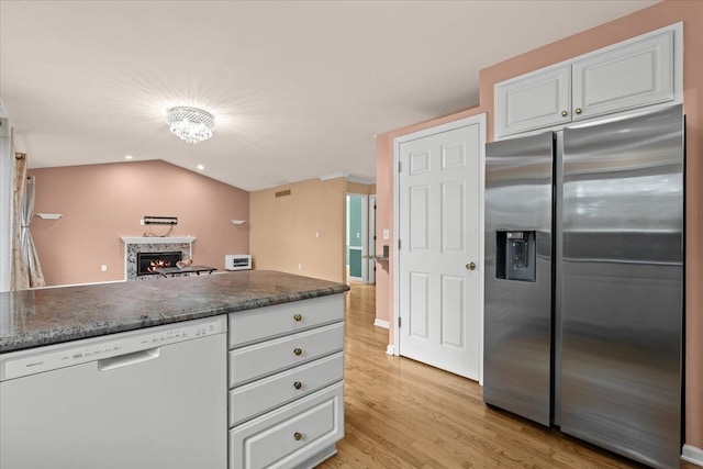 kitchen featuring a warm lit fireplace, stainless steel fridge with ice dispenser, lofted ceiling, white dishwasher, and light wood-style floors