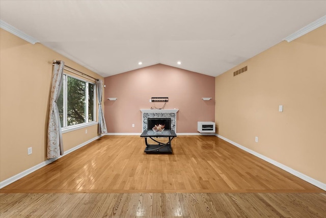 unfurnished living room with baseboards, visible vents, a tiled fireplace, lofted ceiling, and wood finished floors