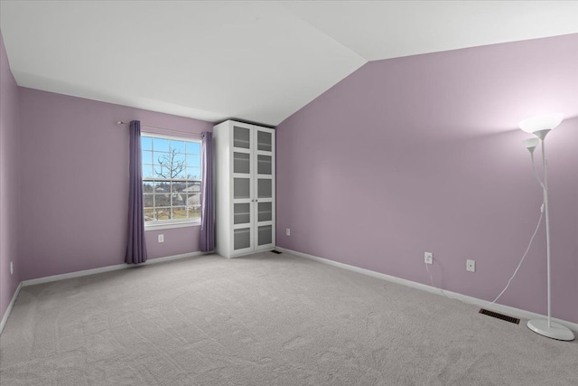 carpeted empty room with visible vents, baseboards, and vaulted ceiling