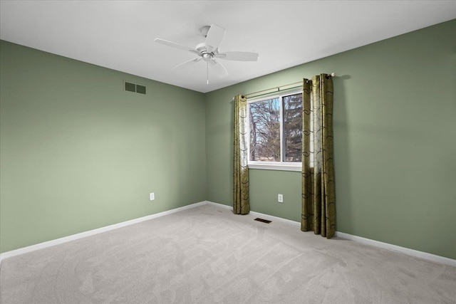 spare room with baseboards, visible vents, ceiling fan, and light colored carpet