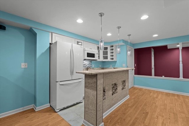 kitchen with pendant lighting, light wood-style flooring, glass insert cabinets, white cabinets, and white appliances