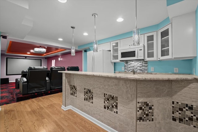 kitchen featuring light stone counters, light wood-style floors, glass insert cabinets, white cabinetry, and white appliances