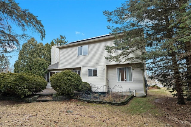 rear view of property featuring a yard and a chimney