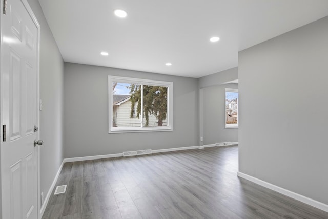 spare room featuring visible vents, baseboards, and wood finished floors