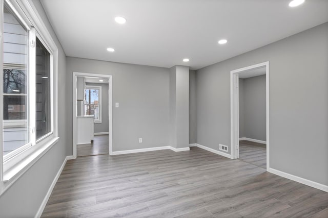 empty room featuring visible vents, baseboards, wood finished floors, and recessed lighting