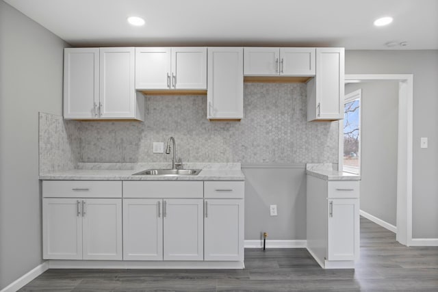 kitchen featuring white cabinets, a sink, and baseboards