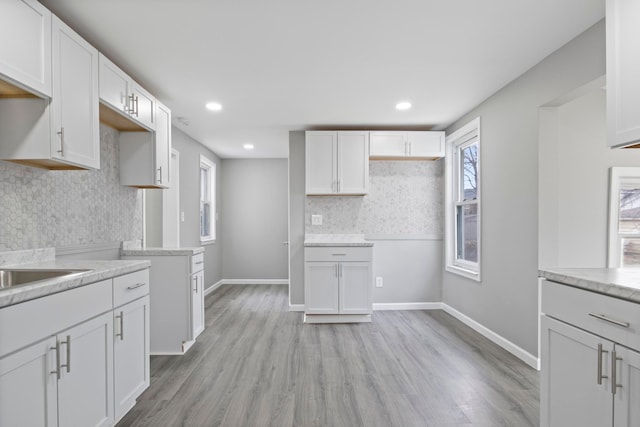 kitchen with light wood-style floors, light countertops, baseboards, and decorative backsplash