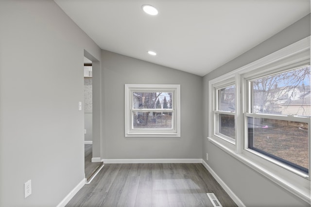 empty room featuring vaulted ceiling, wood finished floors, visible vents, and baseboards