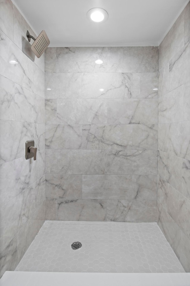 bathroom featuring ornamental molding and a tile shower