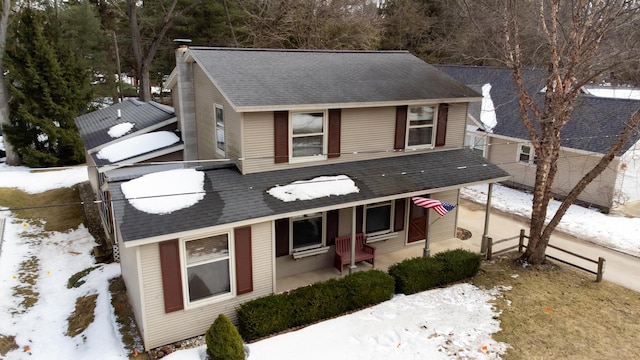 view of front of house featuring a shingled roof, covered porch, and a chimney